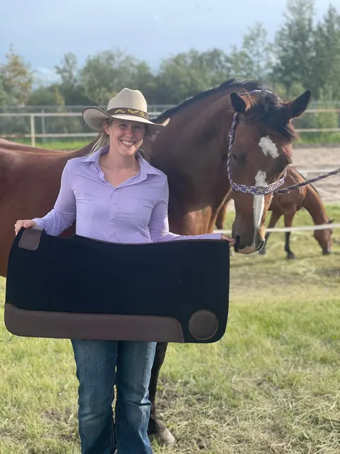 Alyssa with Pushy, holding a saddle pad